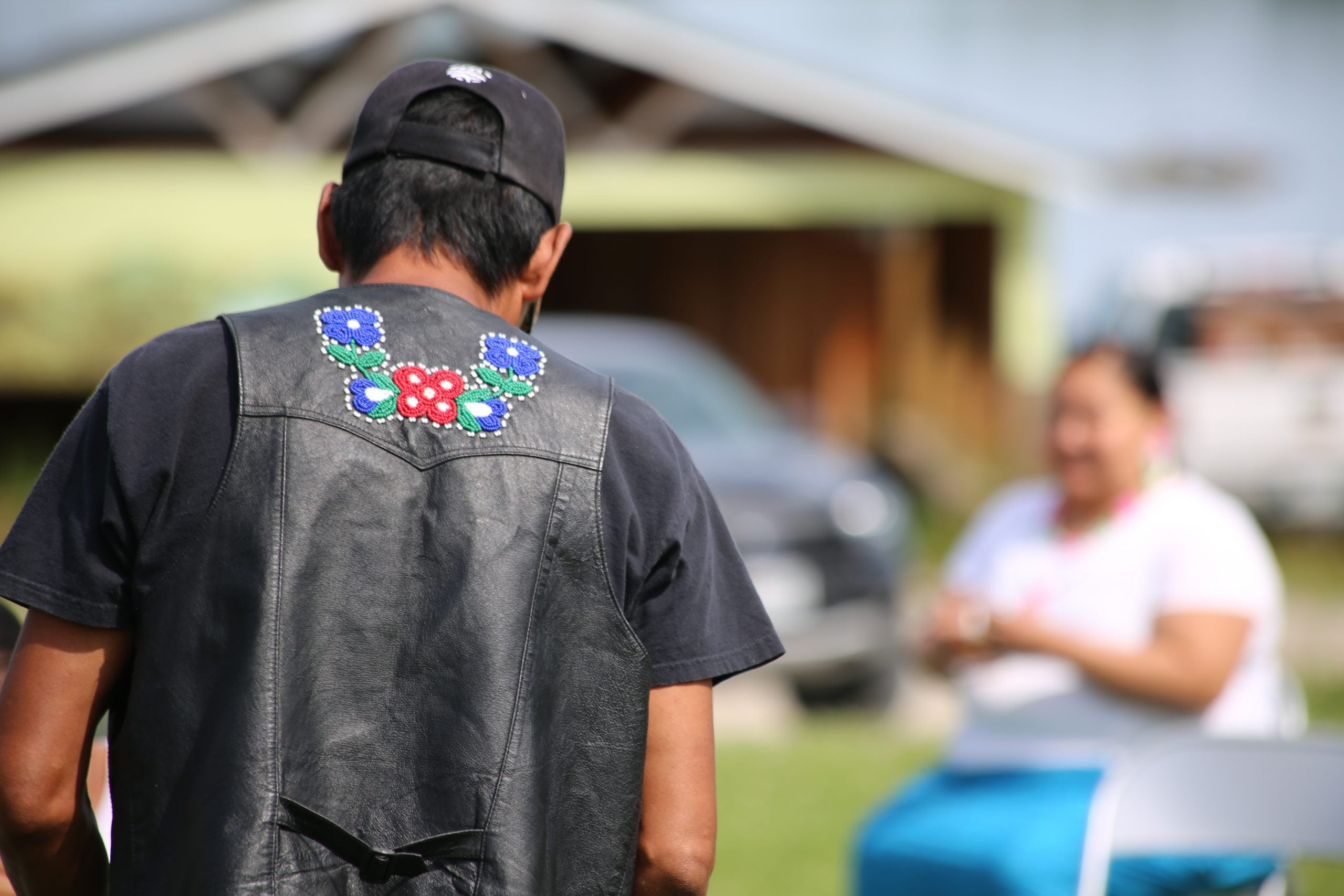 The back of man wearing a letter vest embroidered with beads in the traditional style.